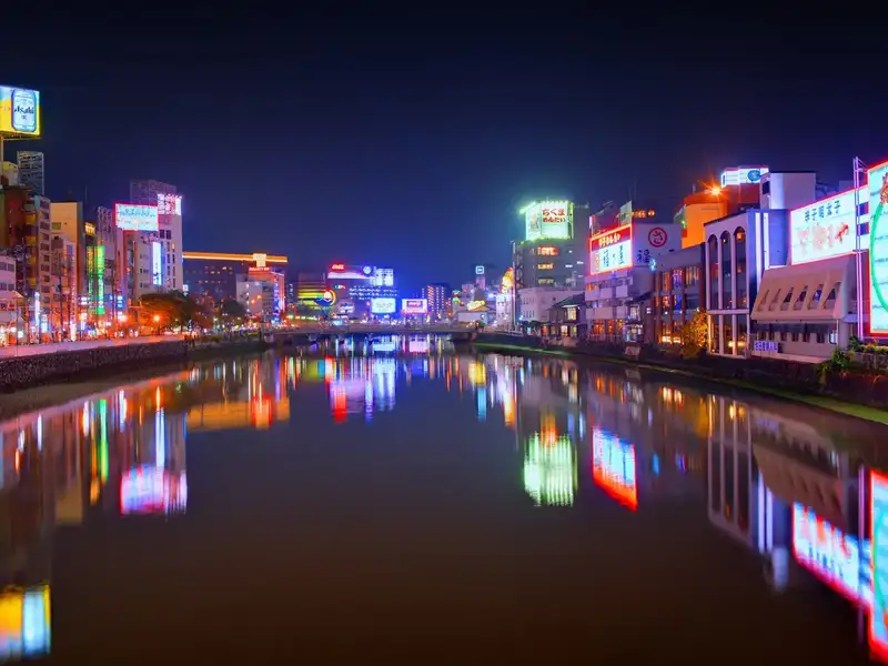 A river running through Fukuoka City illuminated by lights at night