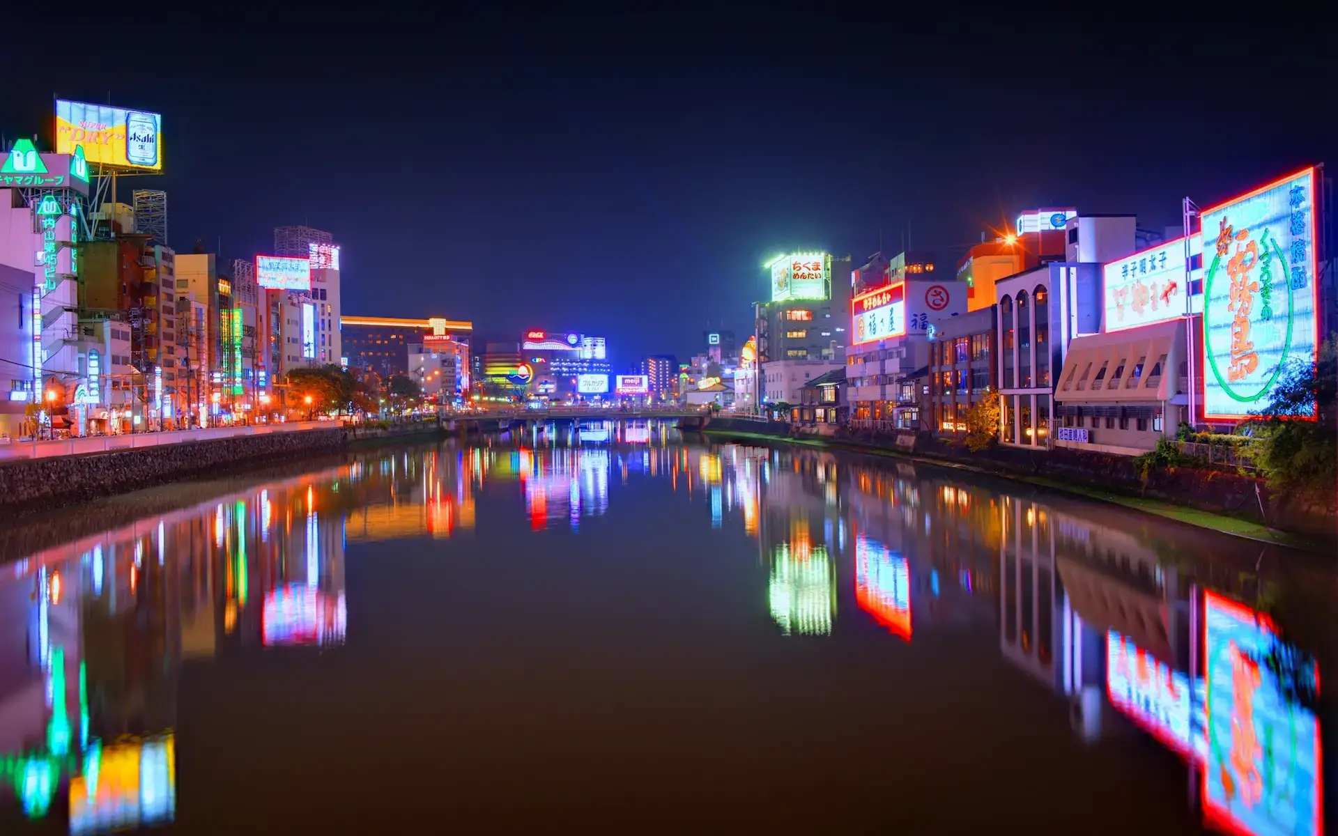 A river running through Fukuoka City illuminated by lights at night