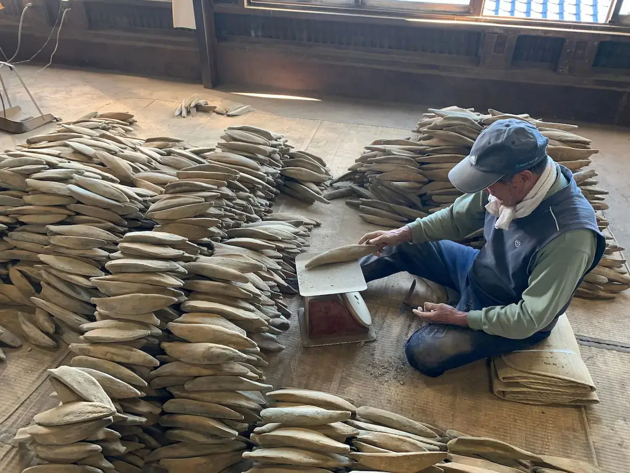 A man sitting with a pile of dried fish used for making bonito flakes